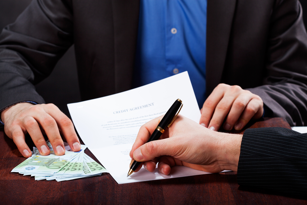 A closeup of a man signing an express cash loan agreement