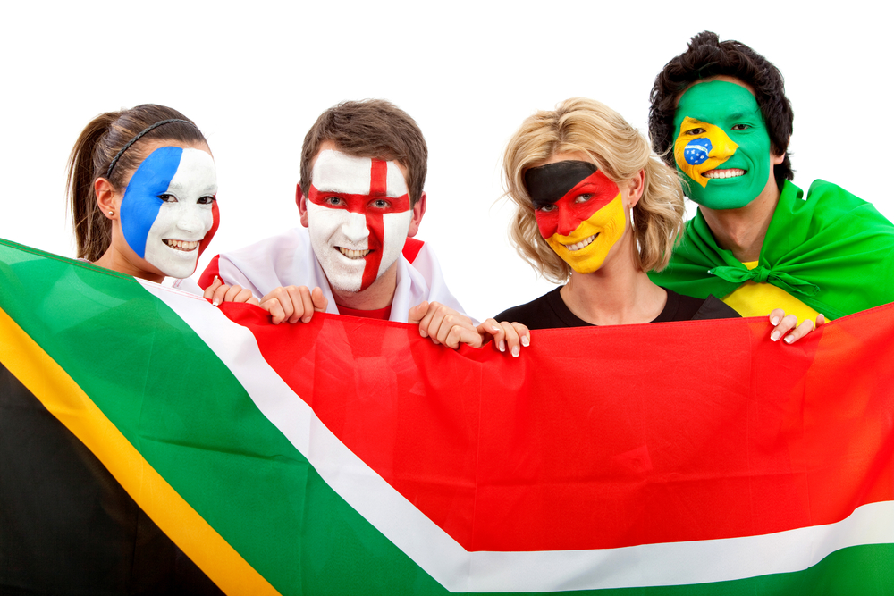 Group of football fans holding a southafrican flag with their faces painted isolated over white-1